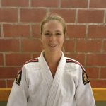 Een foto van Inge Tijssen met judo outfit tegen een stenen muur.