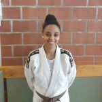 Een foto van Jara Devolder met judo outfit tegen een stenen muur.