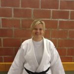 Een foto van Jill Van Laarhoven met judo outfit tegen een stenen muur.