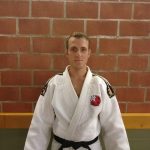 Een foto van Jimmy Thijssen met judo outfit tegen een stenen muur.