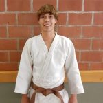 Een foto van Jonas Behiels met judo outfit tegen een stenen muur.
