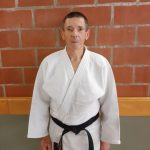 Een foto van Roger Moonen met judo outfit tegen een stenen muur.